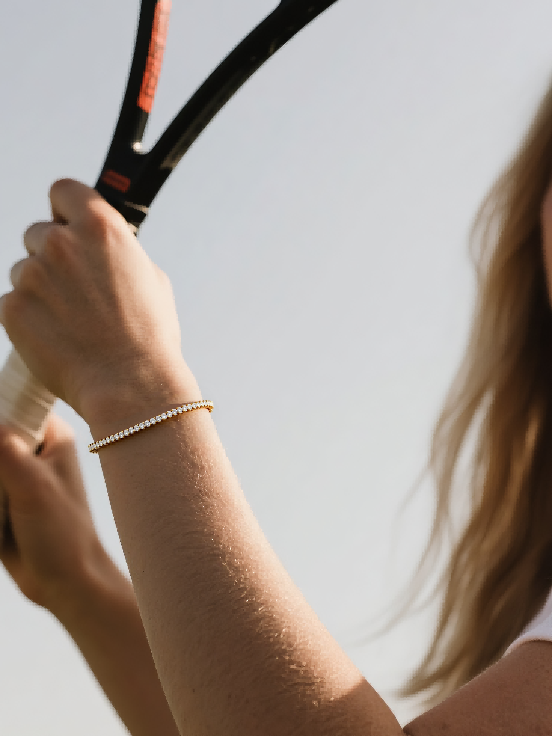 Customer styling diamond tennis bracelet 4mm in 14K gold during tennis match – elegant women’s accessory