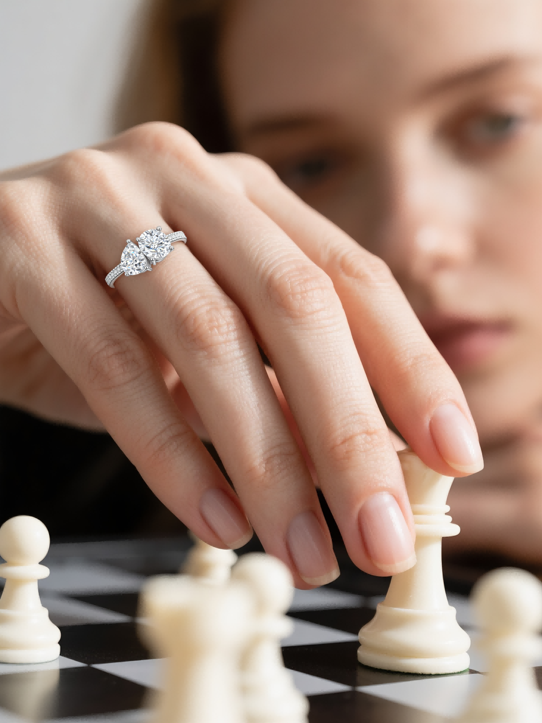 Customer using BuzzBloom twin stone engagement ring while moving white chess piece – stylish women’s detail shot