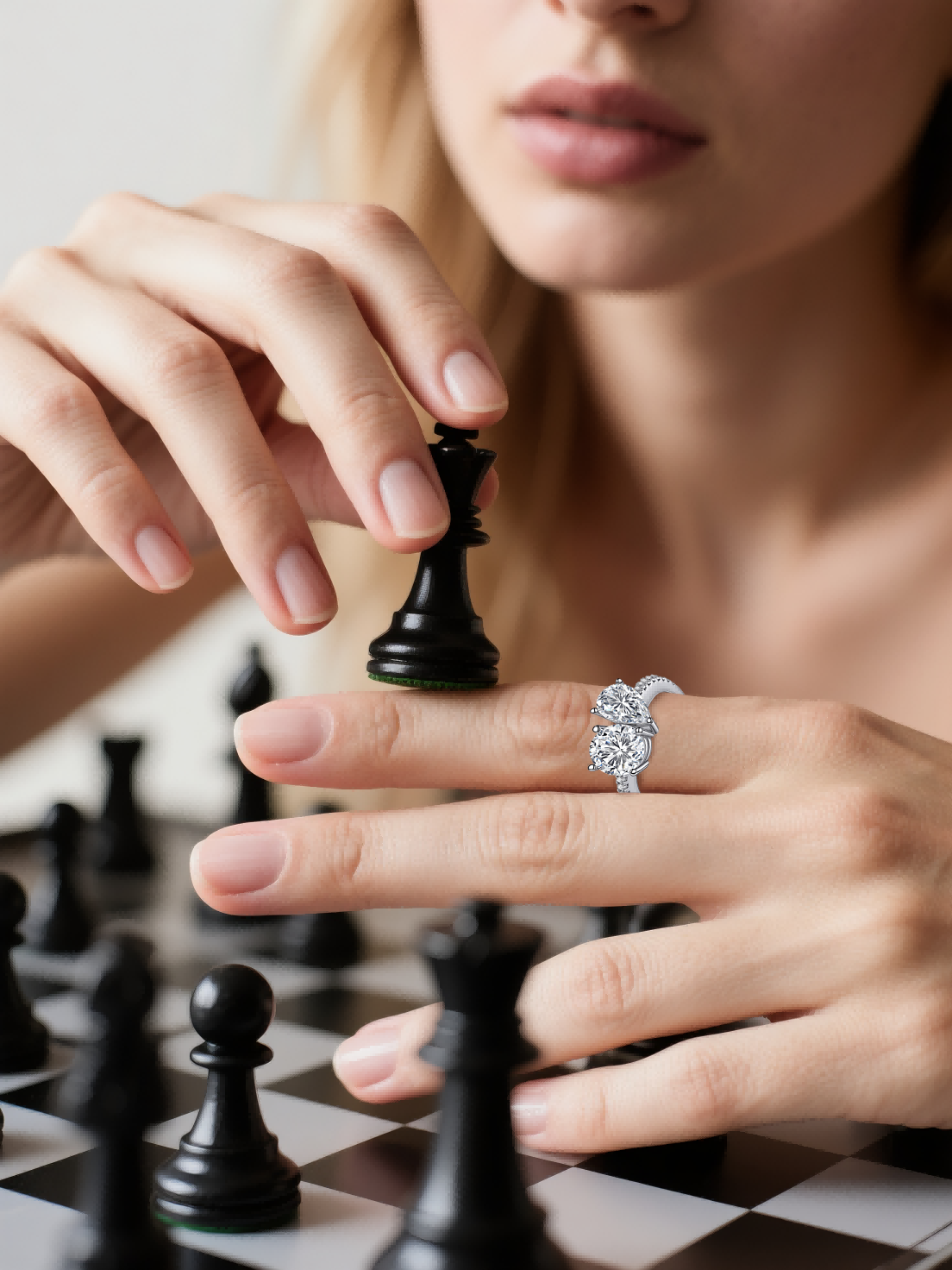 Customer showcasing BuzzBloom pear and round two-stone engagement ring during chess play – sophisticated women’s jewelry close-up