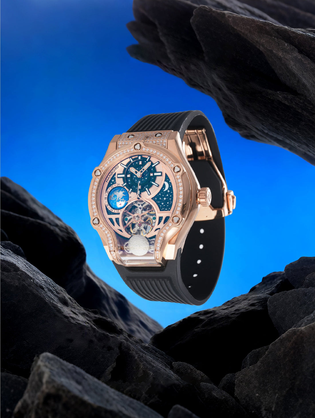 Own Your Bloom Starry Machine Rose Gold Watch displayed among dark rocks and blue background, symbolizing cosmic luxury, Miami.