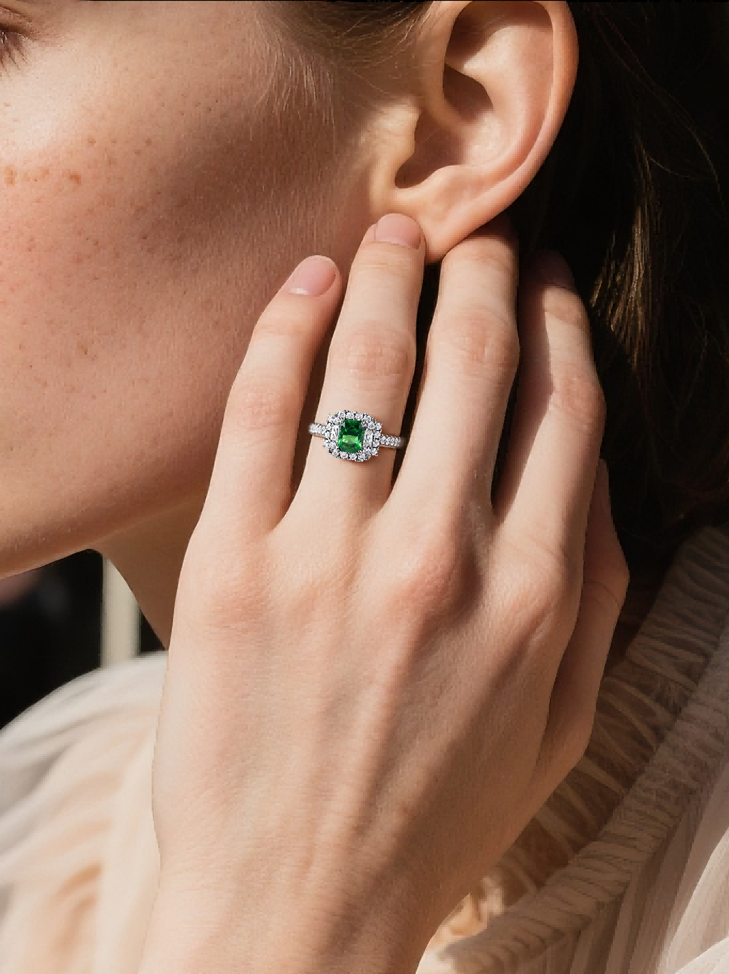 BuzzBloom customer wearing art deco emerald halo engagement ring in indoor elegant detail handshot scene, luxury moissanite jewelry for women
