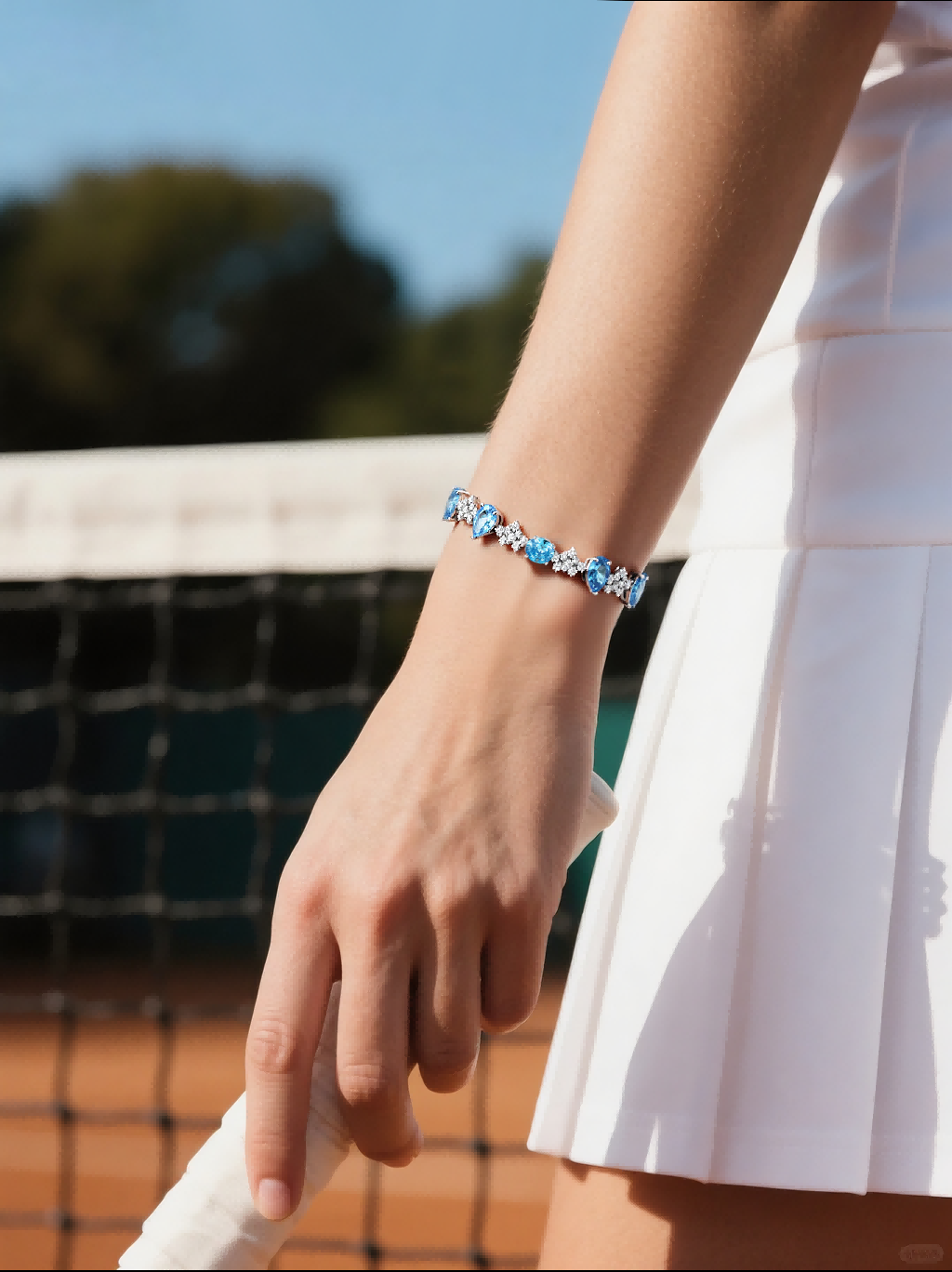 BuzzBloom customer showing luxury sapphire tennis bracelet with blue stones on tennis court, stylish women’s jewelry