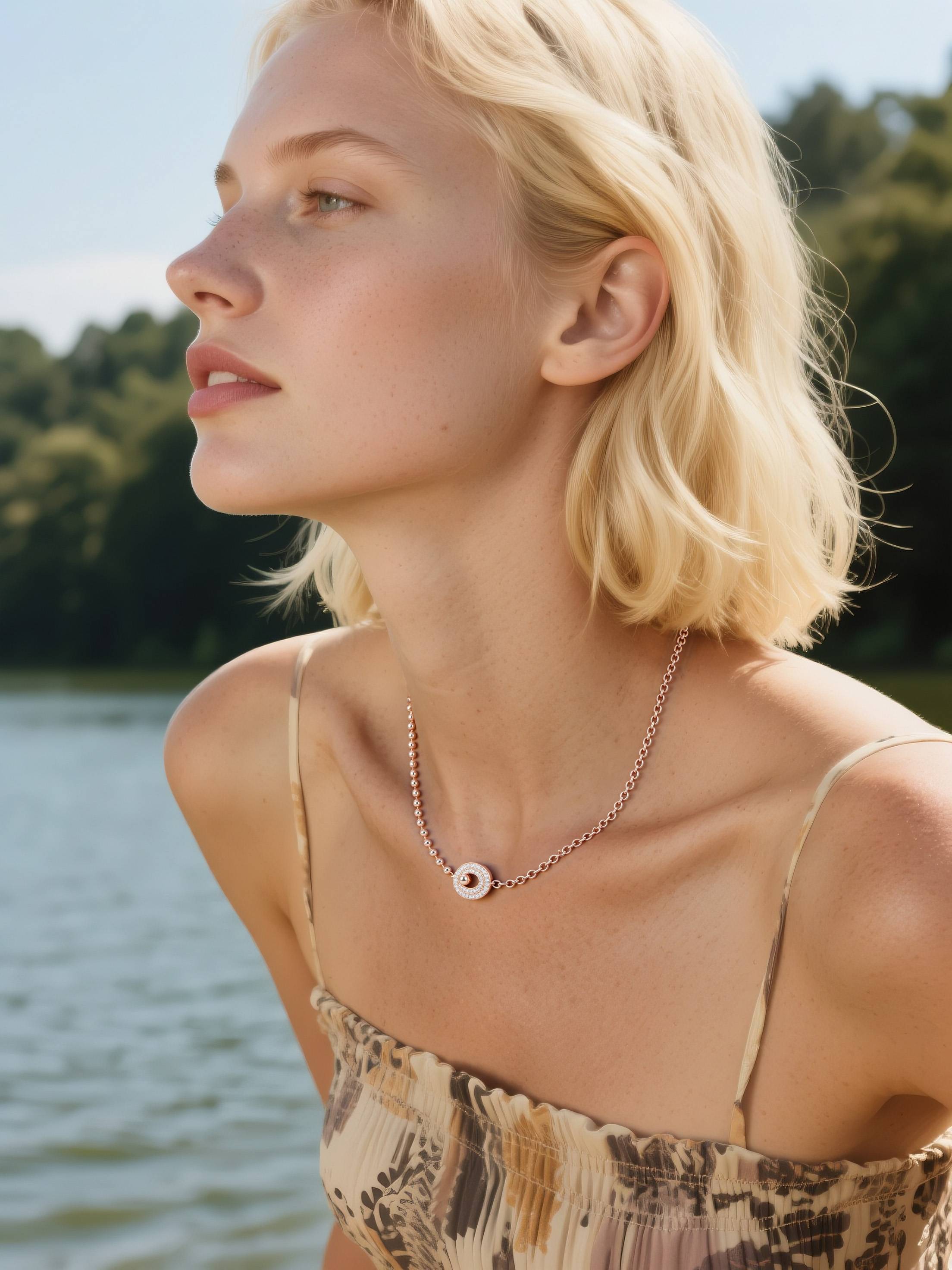 Customer wearing rose gold beaded necklace by the lake, young woman enjoying nature