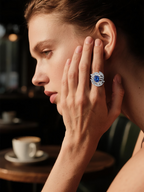 BuzzBloom customer wearing blue gemstone sapphire engagement ring with celestial design inside café, luxury women’s promise jewelry