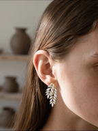 Customer wearing diamond leaf stud earrings close-up in natural light, women’s fine jewelry
