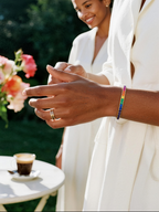 Customer wearing BuzzBloom rainbow diamond tennis bracelet in garden close-up, women’s fine jewelry