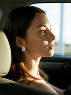 Customer wearing BuzzBloom 14K white gold pear shaped diamond earrings in car, elegant woman