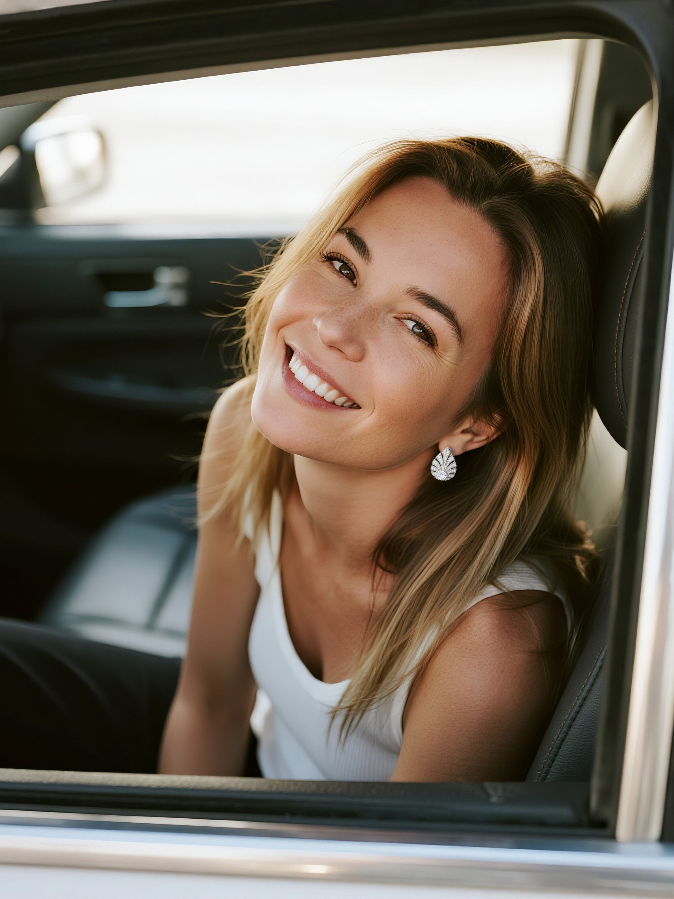 Customer wearing BuzzBloom 14K white gold diamond stud earrings in sunset car scene, modern woman