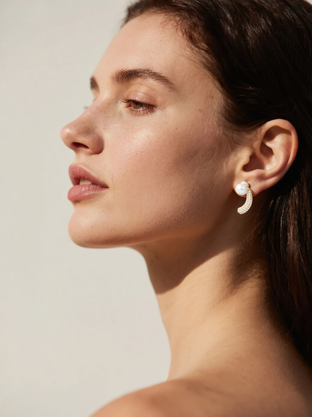 Customer wearing BuzzBloom Australian white shell pearl earrings with pavé diamonds in a minimal studio scene, elegant women’s jewelry