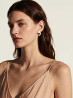 Customer wearing BuzzBloom pearl and diamond stud earrings in a bright lifestyle scene, showcasing elegant women’s fashion