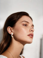 Close-up of customer wearing BuzzBloom luxury pearl stud earrings with pavé diamond detail in a modern lifestyle scene