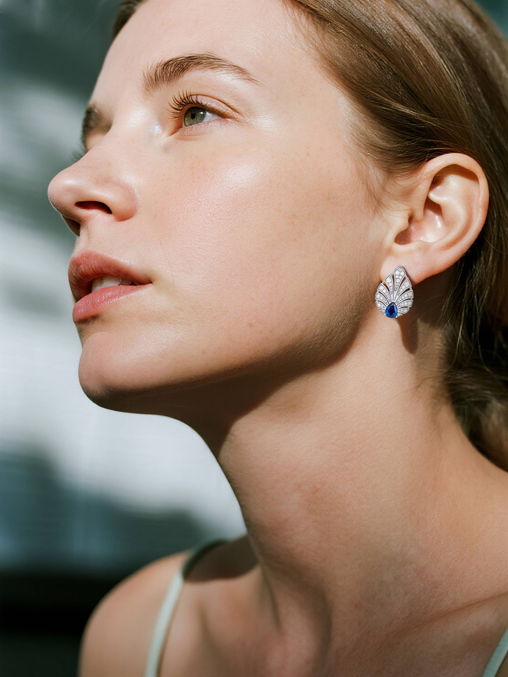 BuzzBloom customer showcasing blue sapphire earrings in natural forest scene, modern women’s fashion