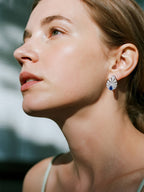 BuzzBloom customer showcasing blue sapphire earrings in natural forest scene, modern women’s fashion