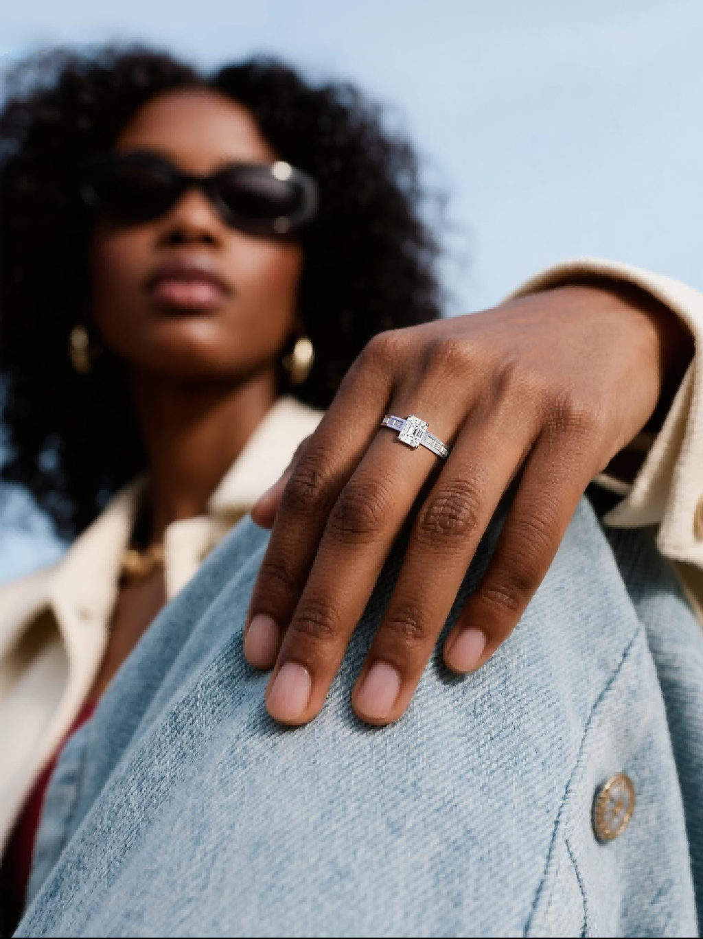 Customer wearing BuzzBloom emerald cut diamond ring in a coffee shop lifestyle scene, modern women’s fine jewelry