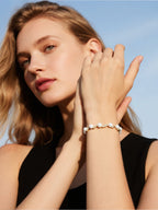 Female model wearing BuzzBloom Australian white shell pearl bracelet with 14k gold and diamonds, outdoor lifestyle close-up for women