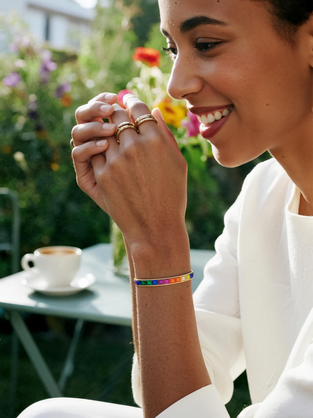 Customer wearing BuzzBloom multicolor diamond bracelet in casual garden setting, women’s rainbow jewelry