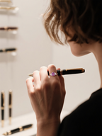 Customer wearing rose gold pink sapphire ring with marquise side stones while holding a pen, elegant lifestyle scene for women