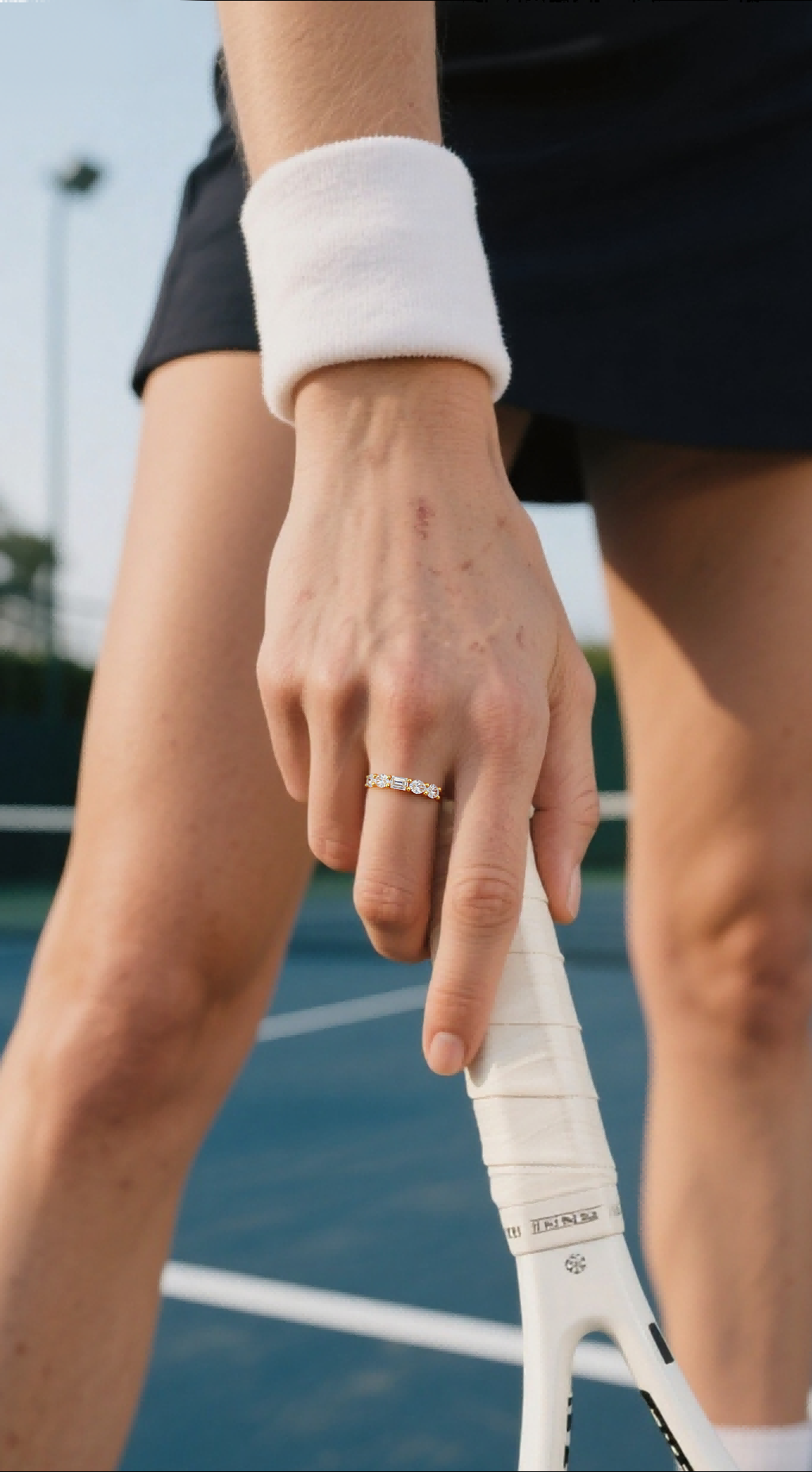Customer wearing BuzzBloom vintage inspired moissanite ring hand close-up on tennis racket, modern women’s accessory