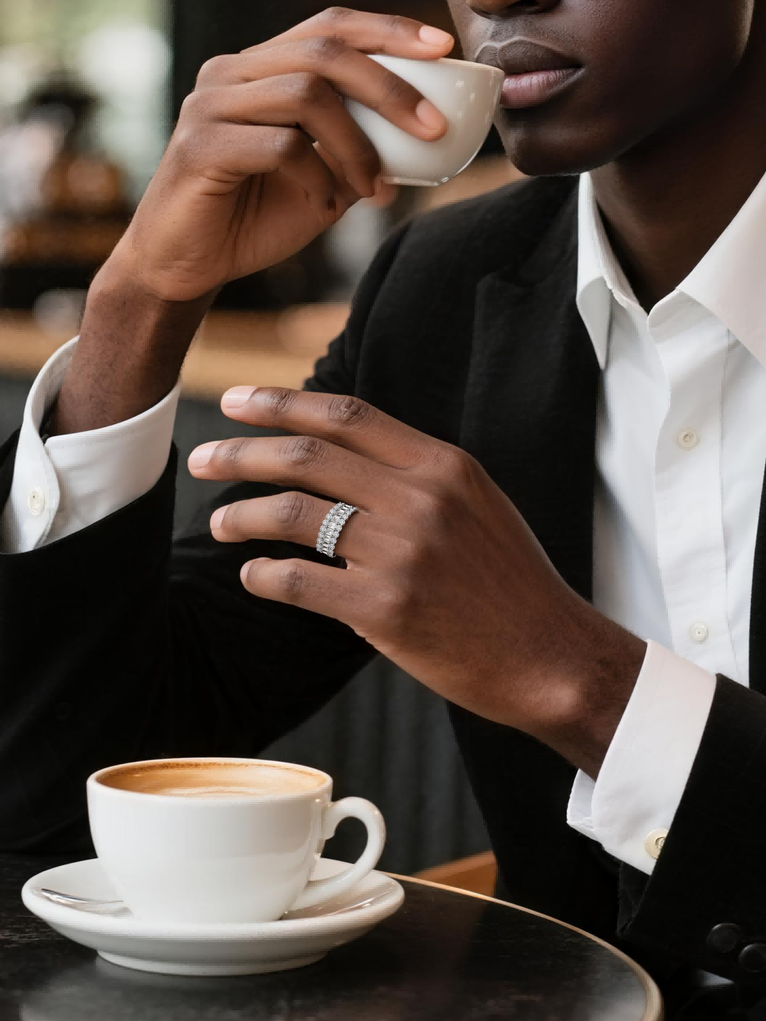 Own Your Bloom luxury 14K diamond ring worn by man holding coffee cup in elegant cafe, sophisticated lifestyle, New York.