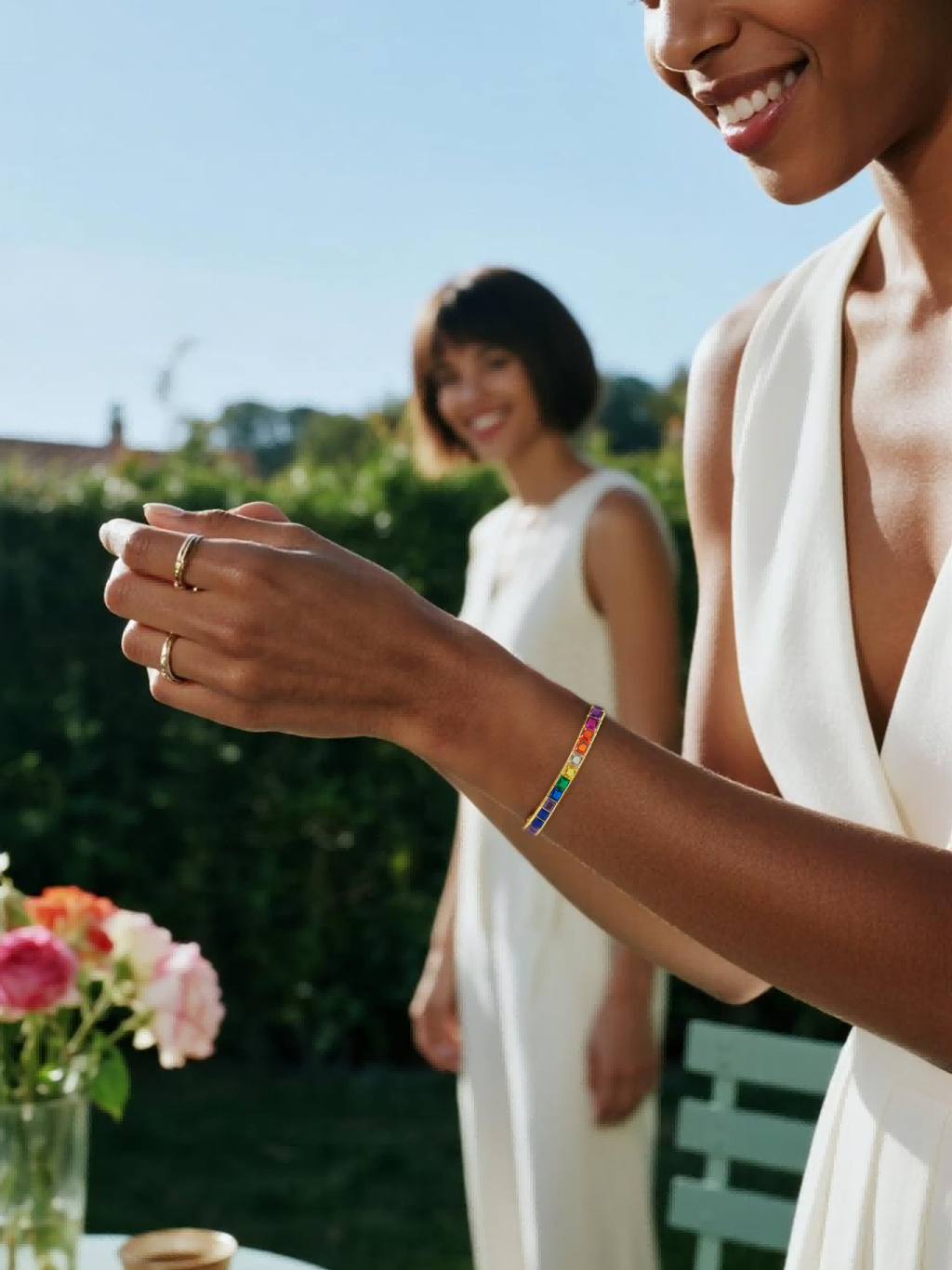 Own Your Bloom 14K rainbow diamond bracelet on woman’s arm with gold rings, luxury outdoor brunch look, Miami.
