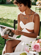 Own Your Bloom rainbow diamond necklace worn by woman, standing garden scene with magazine, Boston.