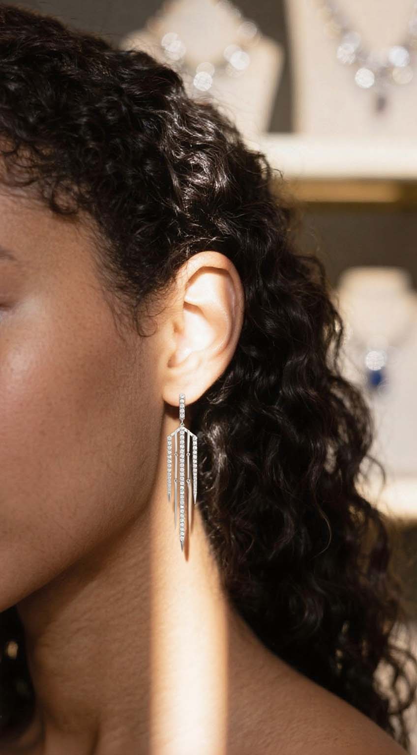 Own Your Bloom 14K tassel line diamond earrings worn by woman in elegant jewelry boutique setting, radiant fine jewelry, New York.