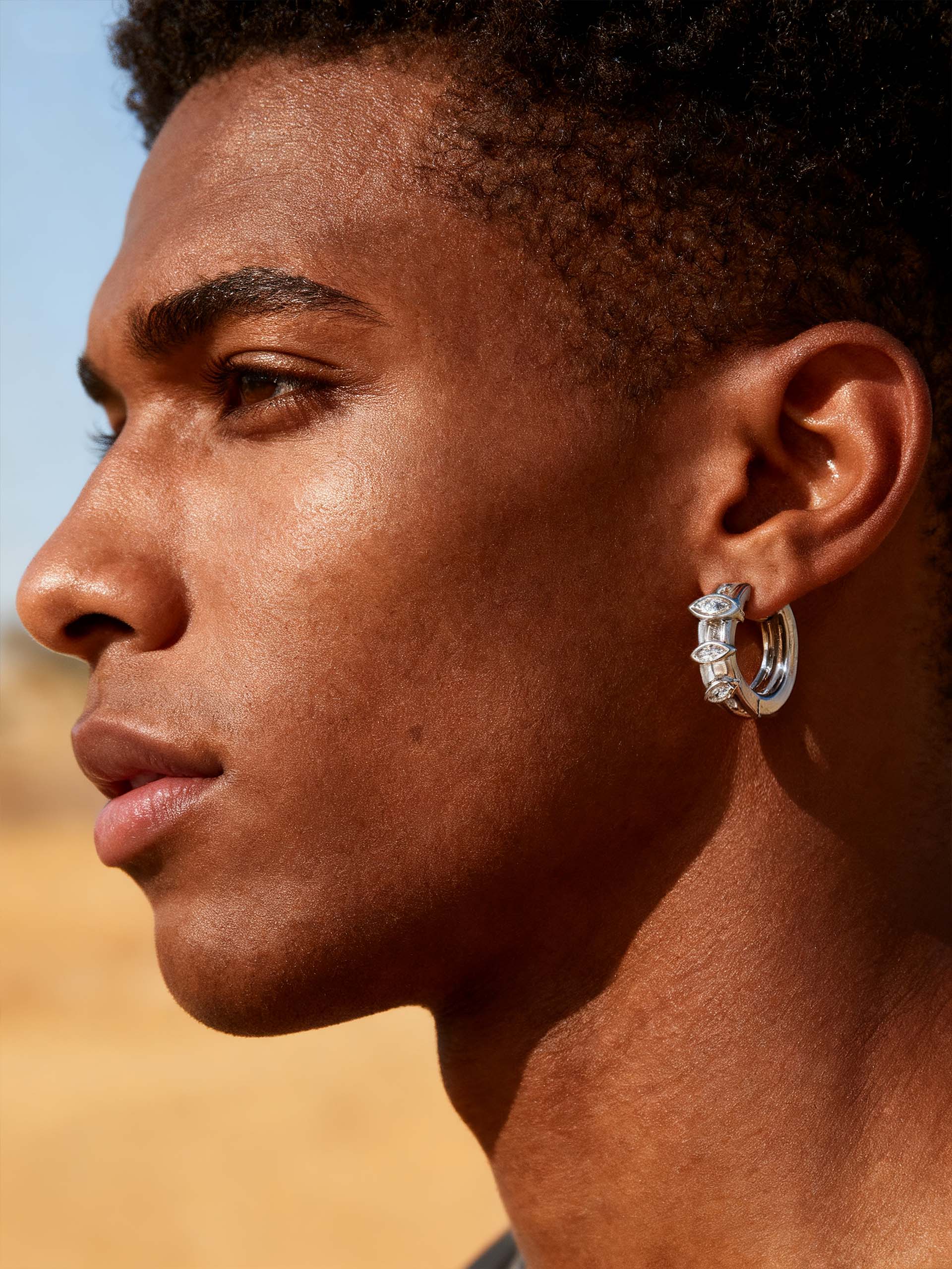 Outdoor side-profile of a man wearing Own Your Bloom 14K white gold marquise diamond hoop earrings, Phoenix.