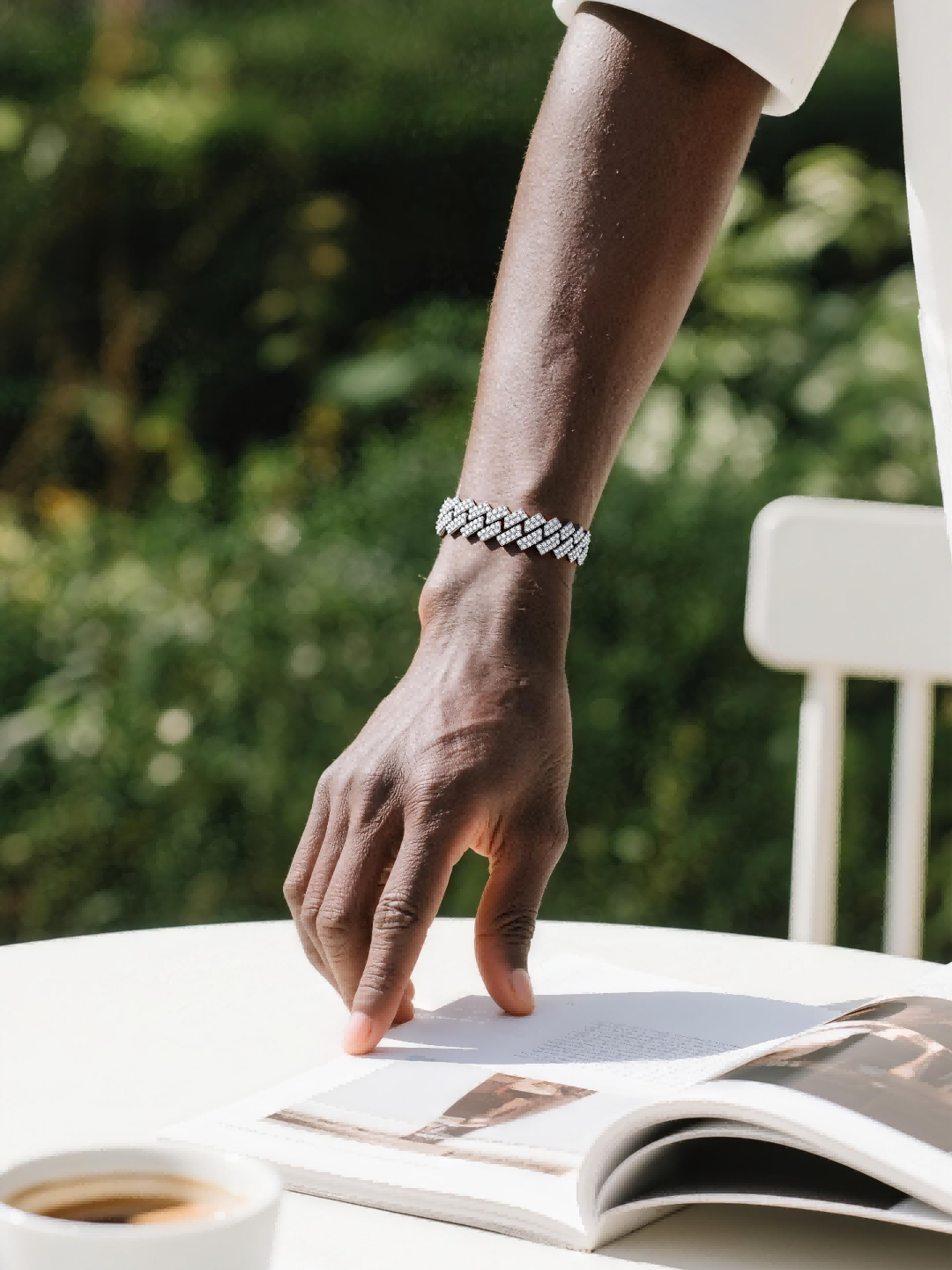 Own Your Bloom 14mm diamond Cuban bracelet on man enjoying coffee, elegant luxury lifestyle jewelry, New York.