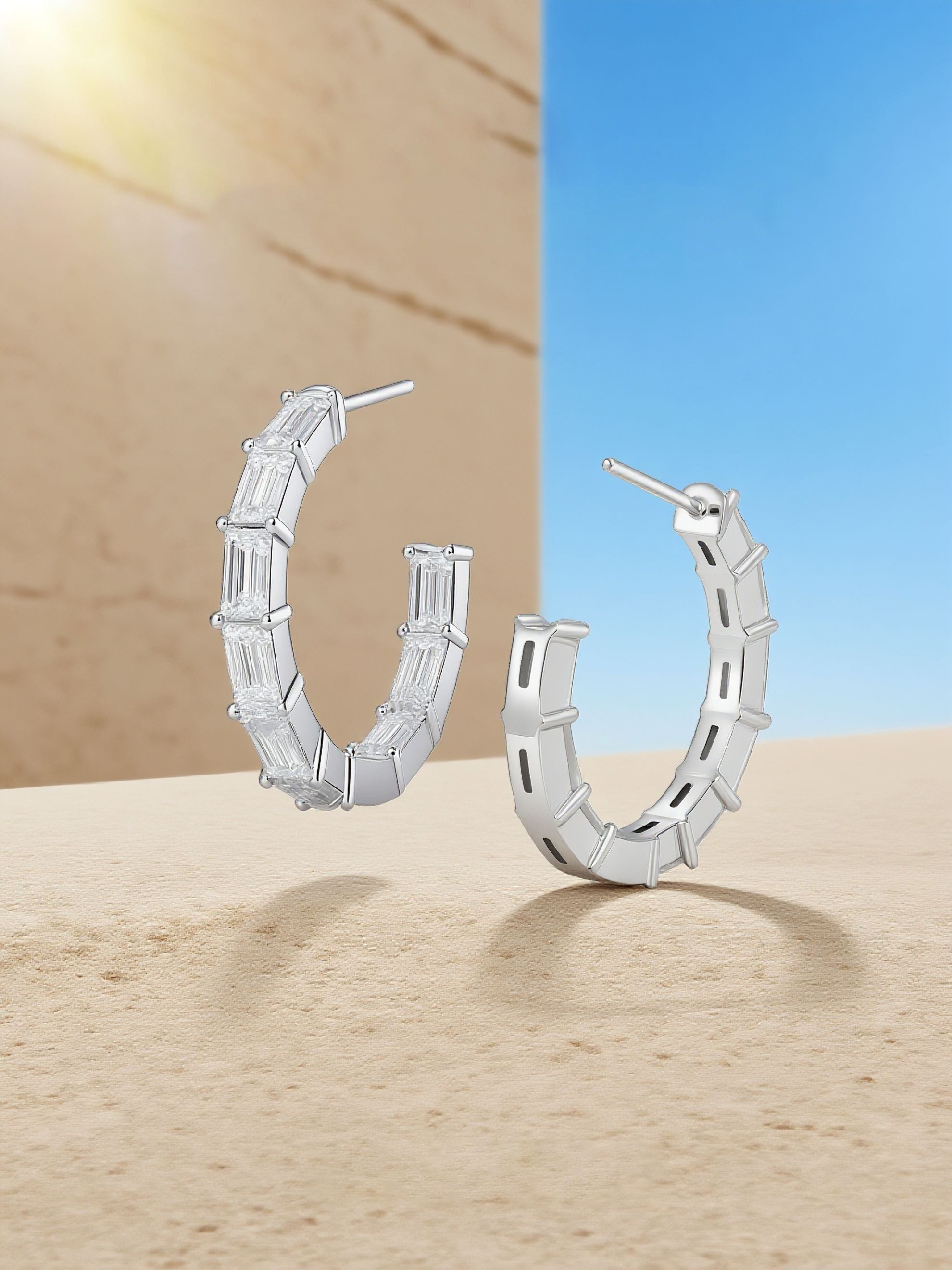 Own Your Bloom moissanite baguette hoop earrings displayed under natural sunlight on sand surface, radiant sparkle and summer luxury, Miami.