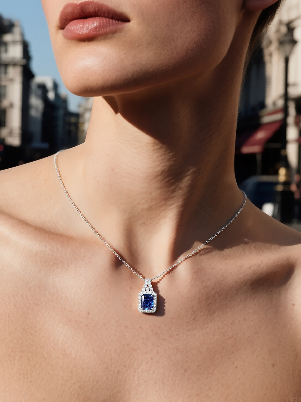 Own Your Bloom radiant blue sapphire necklace worn by woman, timeless gemstone elegance with halo diamond shine, Los Angeles.
