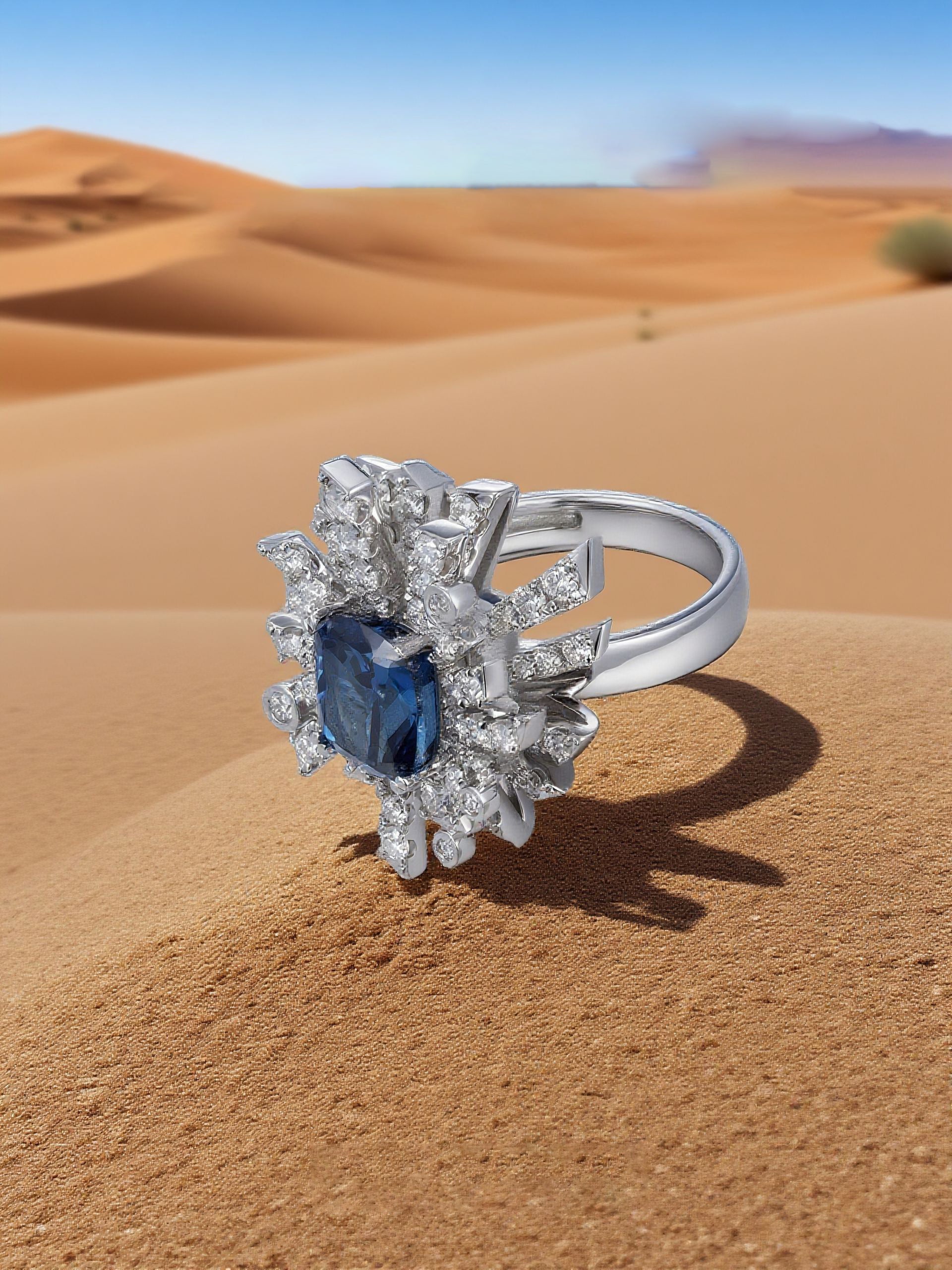 Own Your Bloom Blue Sapphire Floral Ring displayed on soft sand backdrop, reflecting desert-inspired elegance and royal charm, Miami.