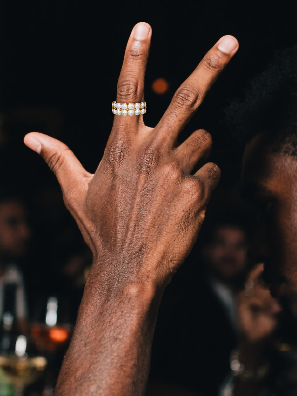 Hand holding a champagne flute while wearing the Own Your Bloom white-gold-plated double-row eternity ring.