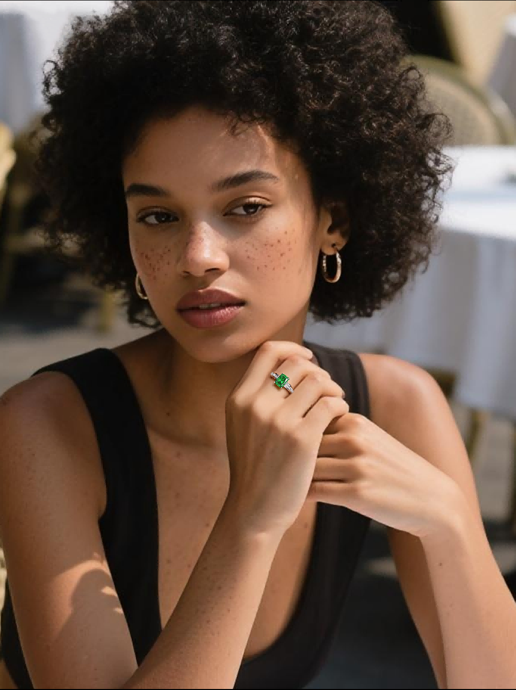 Own Your Bloom emerald cut baguette ring on woman’s hand in café setting, timeless fine jewelry elegance, Miami.
