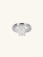 Own Your Bloom emerald-cut diamond engagement ring with baguette side stones, front view on white background, New York.