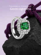 Own Your Bloom green emerald diamond halo ring on black rock with soft purple background, symbolizing timeless luxury, Dallas.