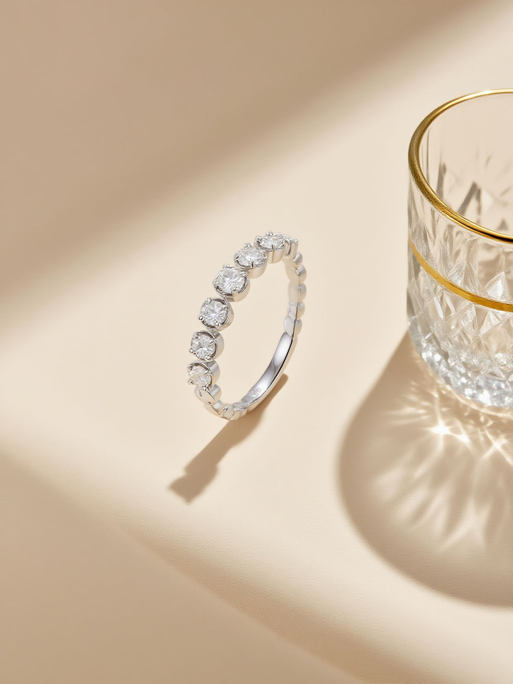 Own Your Bloom Endless Allure diamond eternity band photographed on beige surface with shadow and crystal reflections, Dallas.