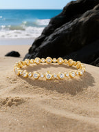Own Your Bloom gold diamond tennis bracelet arranged on natural rock setting by the coast, timeless fine jewelry craftsmanship, Boston.