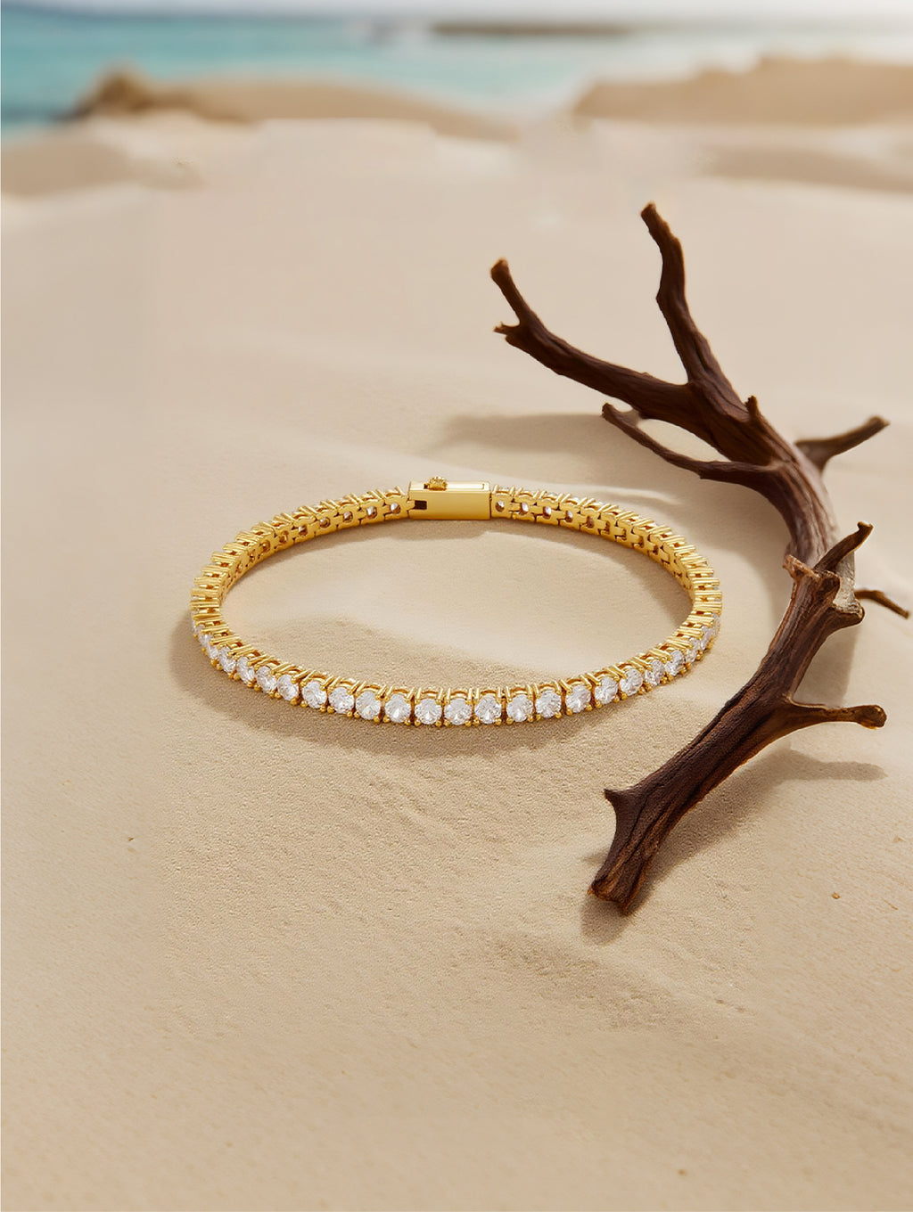 Own Your Bloom Radiant Rhythm Gold Tennis Bracelet resting on beach setting, symbolizing timeless sparkle and refinement, Boston.