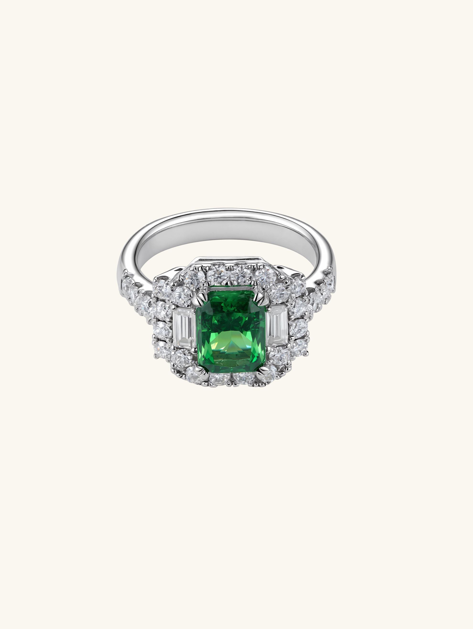 Own Your Bloom emerald halo baguette round ring front view in white gold, featuring green gemstone center surrounded by round diamonds, fine jewelry, New York.