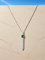 Own Your Bloom green gemstone tassel necklace showcased against architectural lighting emphasizing balance and brilliance, Dallas.