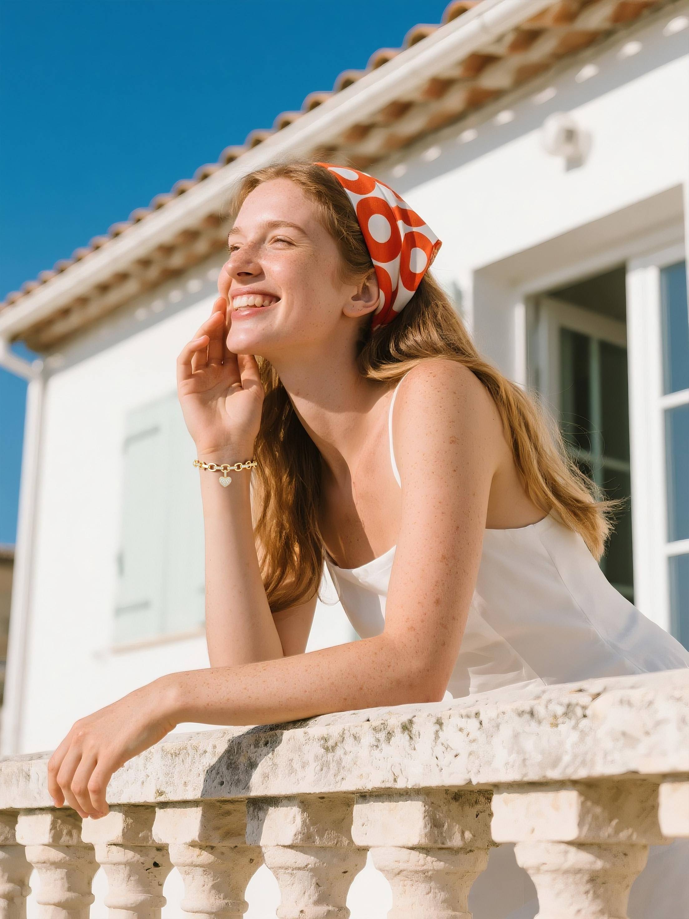 Own Your Bloom Heart Charm Bracelet on woman’s wrist, styled with white dress and golden light, symbolizing modern femininity, Los Angeles.