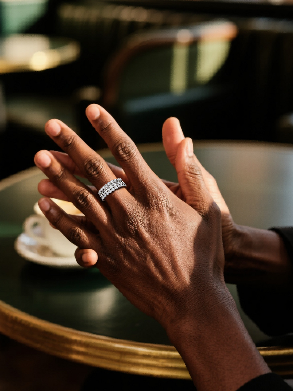 Own Your Bloom luxury 14K diamond ring on man’s hand under warm café lighting, timeless elegance, Los Angeles.