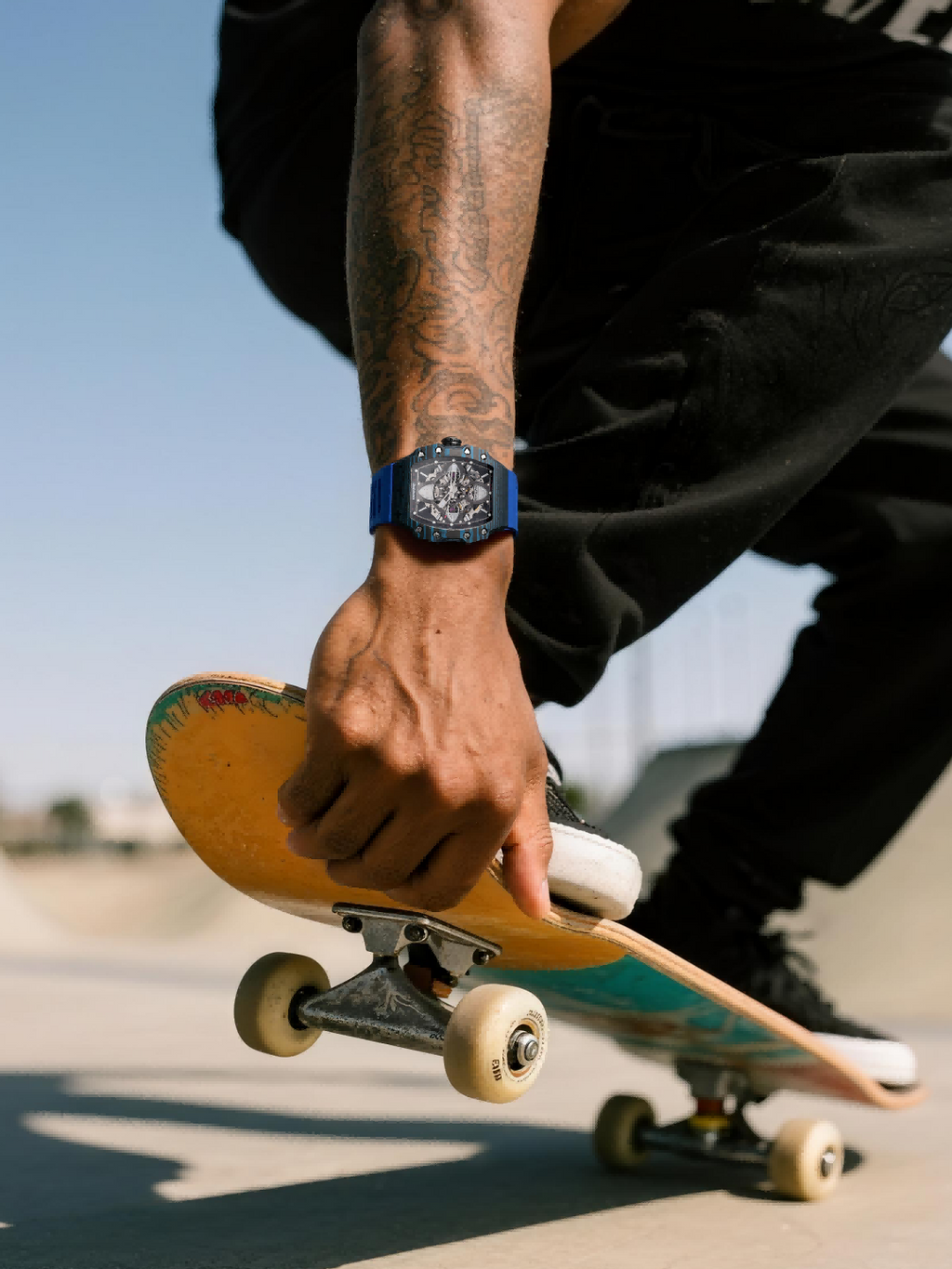 Own Your Bloom 304 stainless steel skeleton watch on man’s wrist holding skateboard, skatepark lifestyle, Houston.