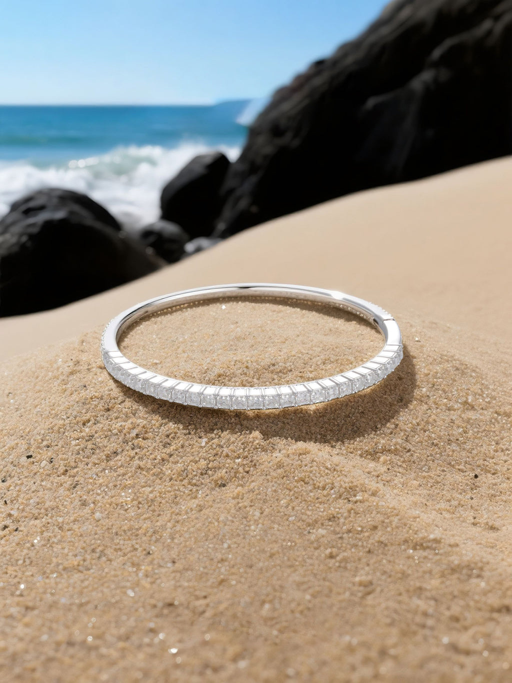 Own Your Bloom moissanite bangle tennis bracelet displayed on seaside rocks with ocean background, radiant fine jewelry, Miami.