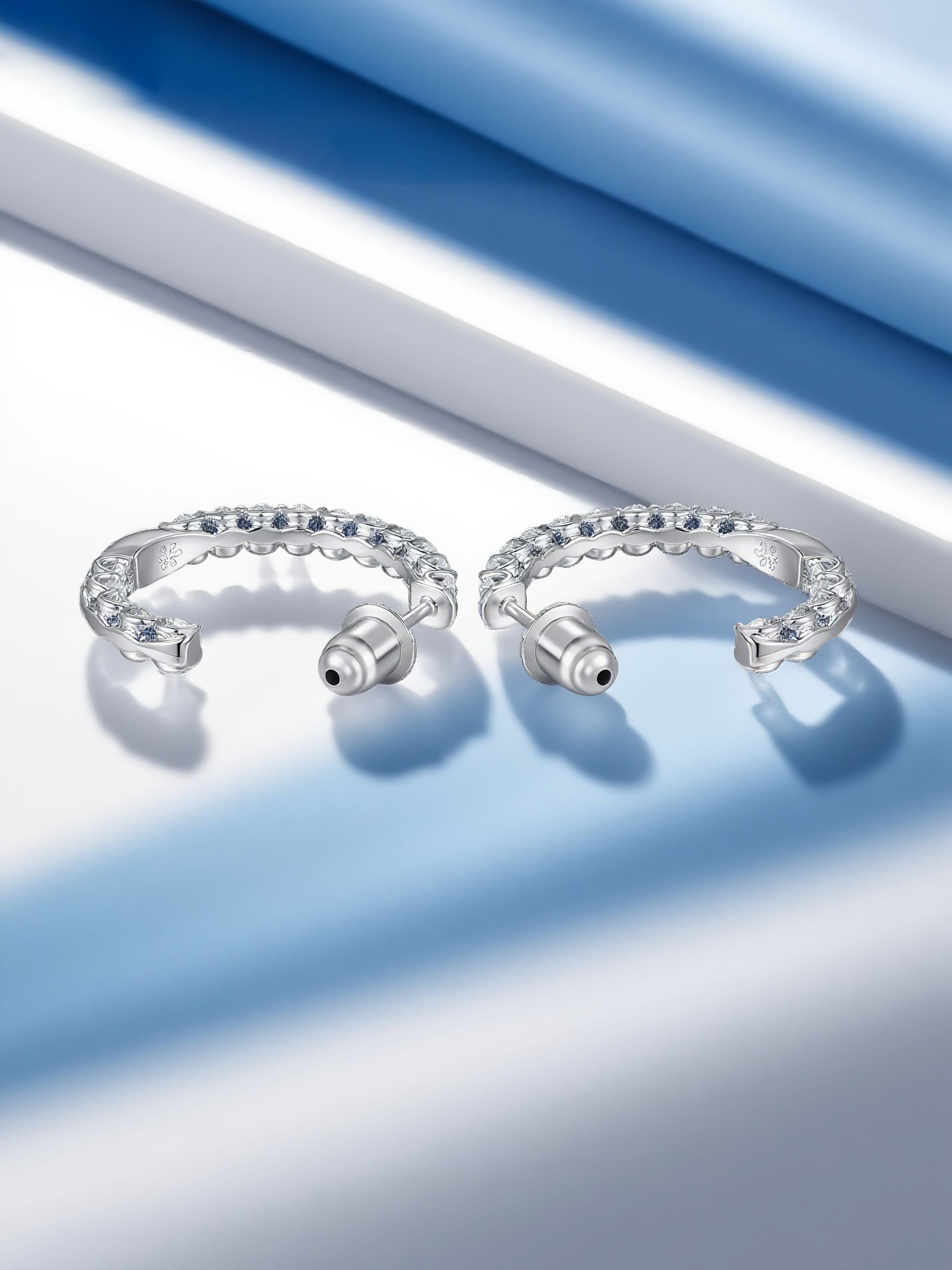 Own Your Bloom moissanite half hoop earrings displayed under spotlight, representing timeless brilliance and luxury craftsmanship, Miami.