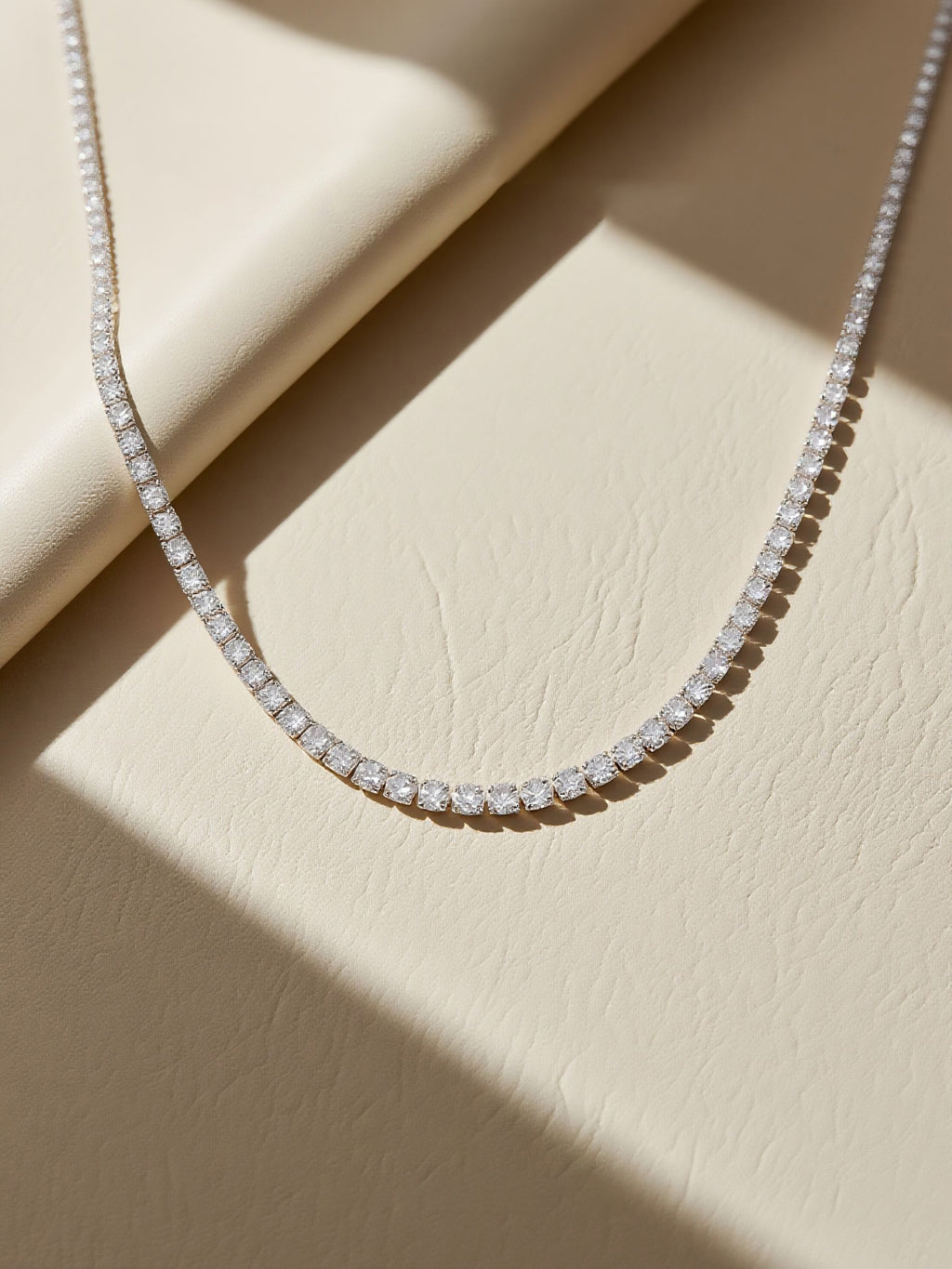 Own Your Bloom moissanite tennis necklace displayed under warm sunlight on textured surface, timeless sparkle and sophistication, Miami.