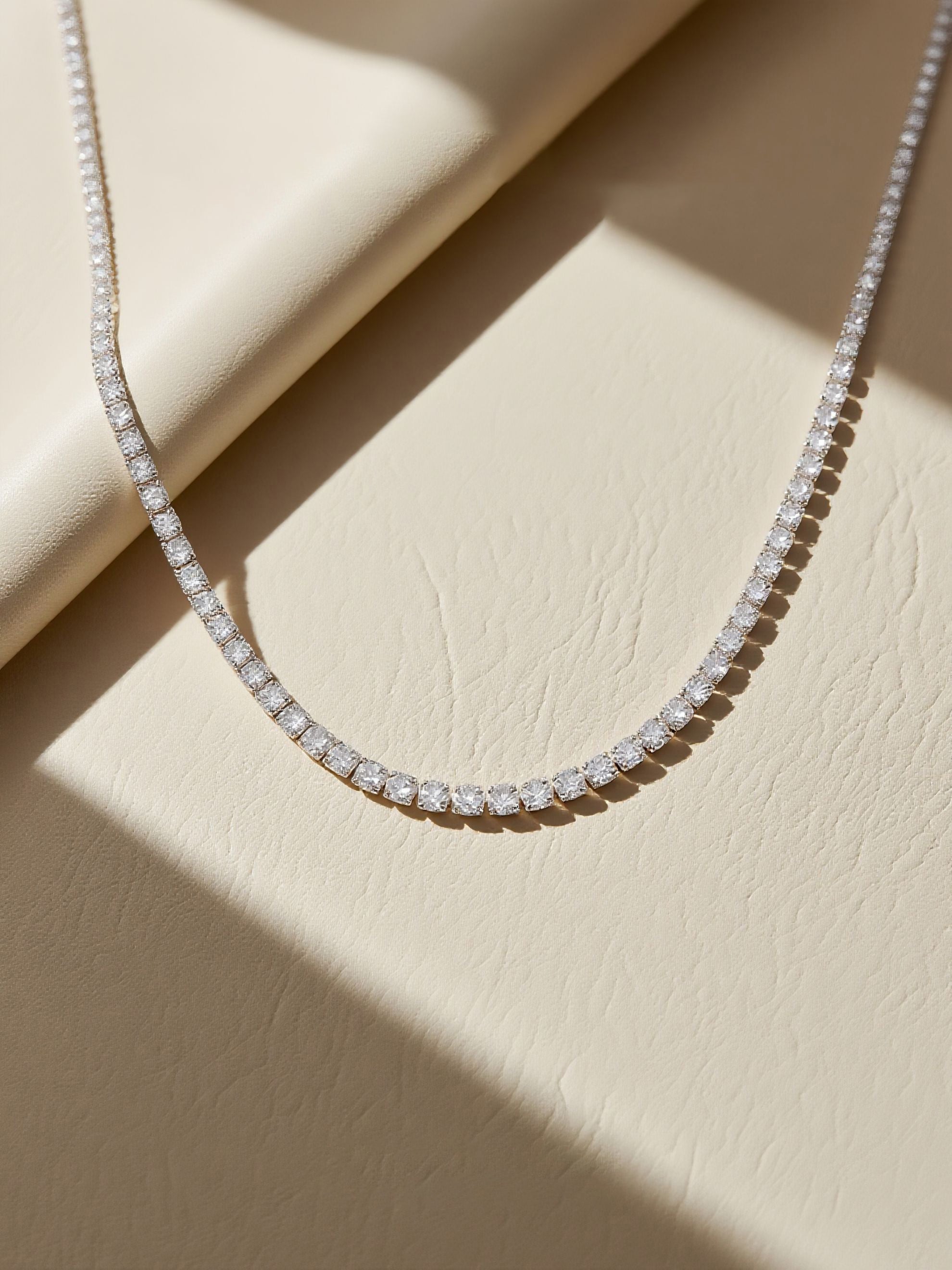 Own Your Bloom moissanite tennis necklace displayed under warm sunlight on textured surface, timeless sparkle and sophistication, Miami.