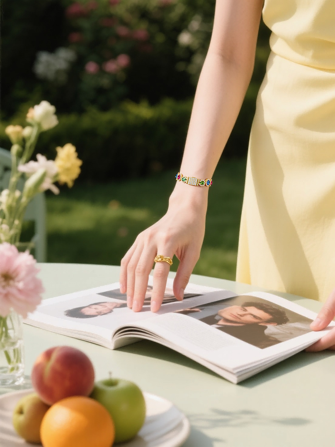 Own Your Bloom 14K gold bracelet with colorful gemstones worn by woman reading magazine outdoors, Boston.