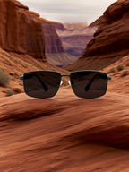 Own Your Bloom aerospace-grade nylon sunglasses placed on red desert rock under clear sky, modern travel lifestyle, Utah.
