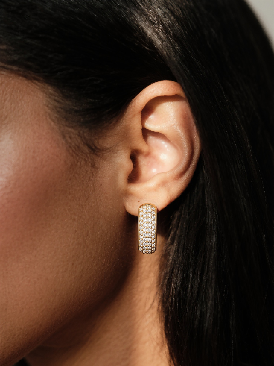 Woman wearing Own Your Bloom 14K gold-plated pavé hoop earring, close-up on ear.